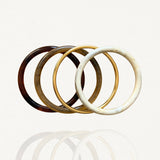 Ensemble de quatre bracelets joncs rigides : résine motif écaille de tortue foncée et claire, effet marbre blanc et métal doré simple sur fond blanc.