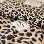Gros plan sur les pochettes en tissu motif léopard avec étiquette brodée 'Amour' et petits cœurs.